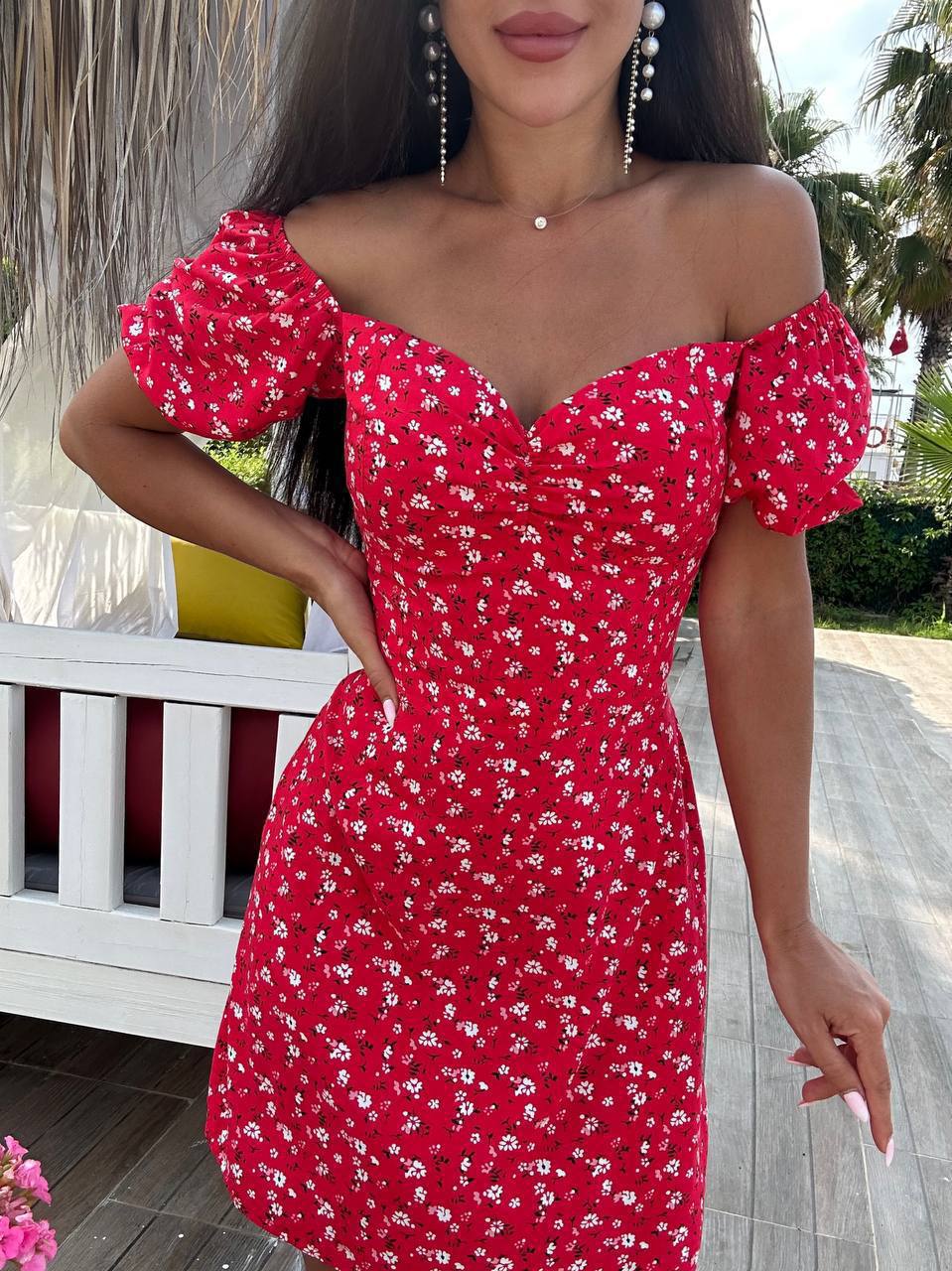 Woman wearing a red floral off-shoulder dress outdoors.