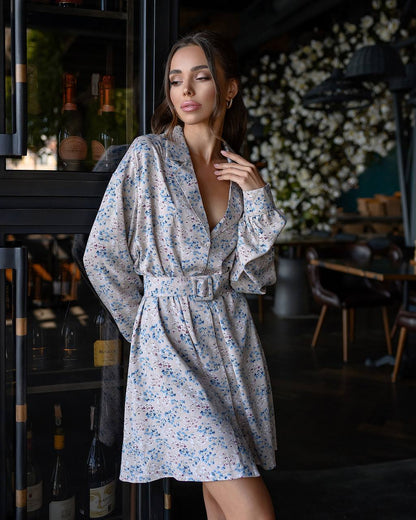 Woman in a floral dress standing in a dimly lit room with decorative elements.