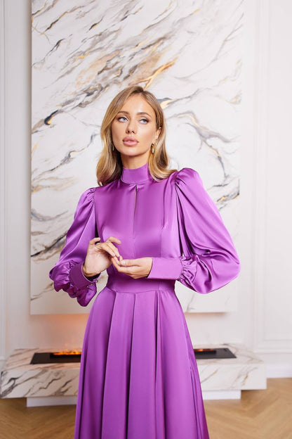 Woman in a purple dress standing in front of a marble wall.
