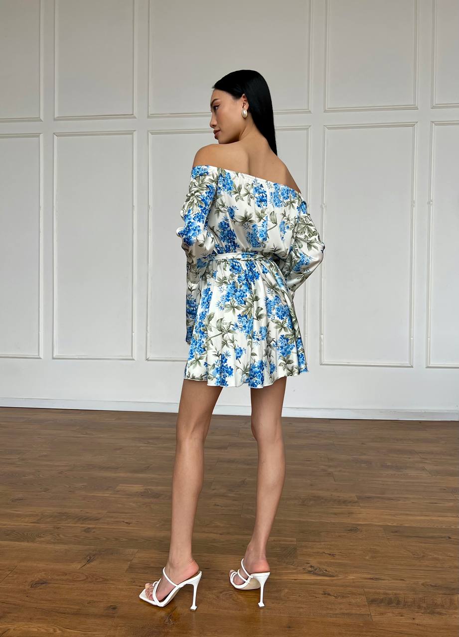 Woman wearing a floral off-shoulder dress in a minimalistic room.