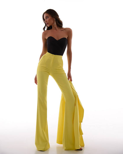 Woman wearing a black strapless top and yellow high-waisted pants on a white background
