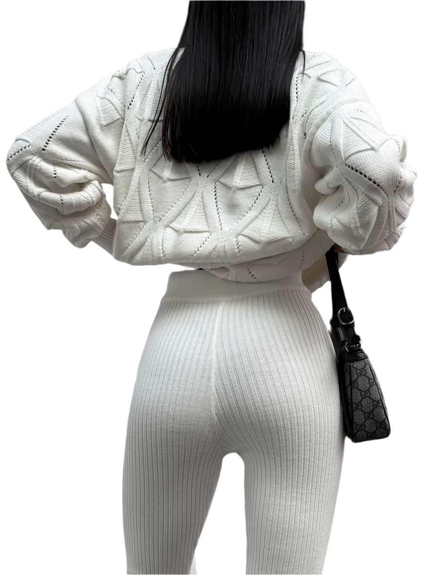 Person wearing a white knit outfit with a black handbag on a white background