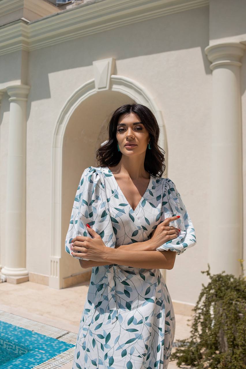 Woman in a floral dress standing in front of a classical building with columns.