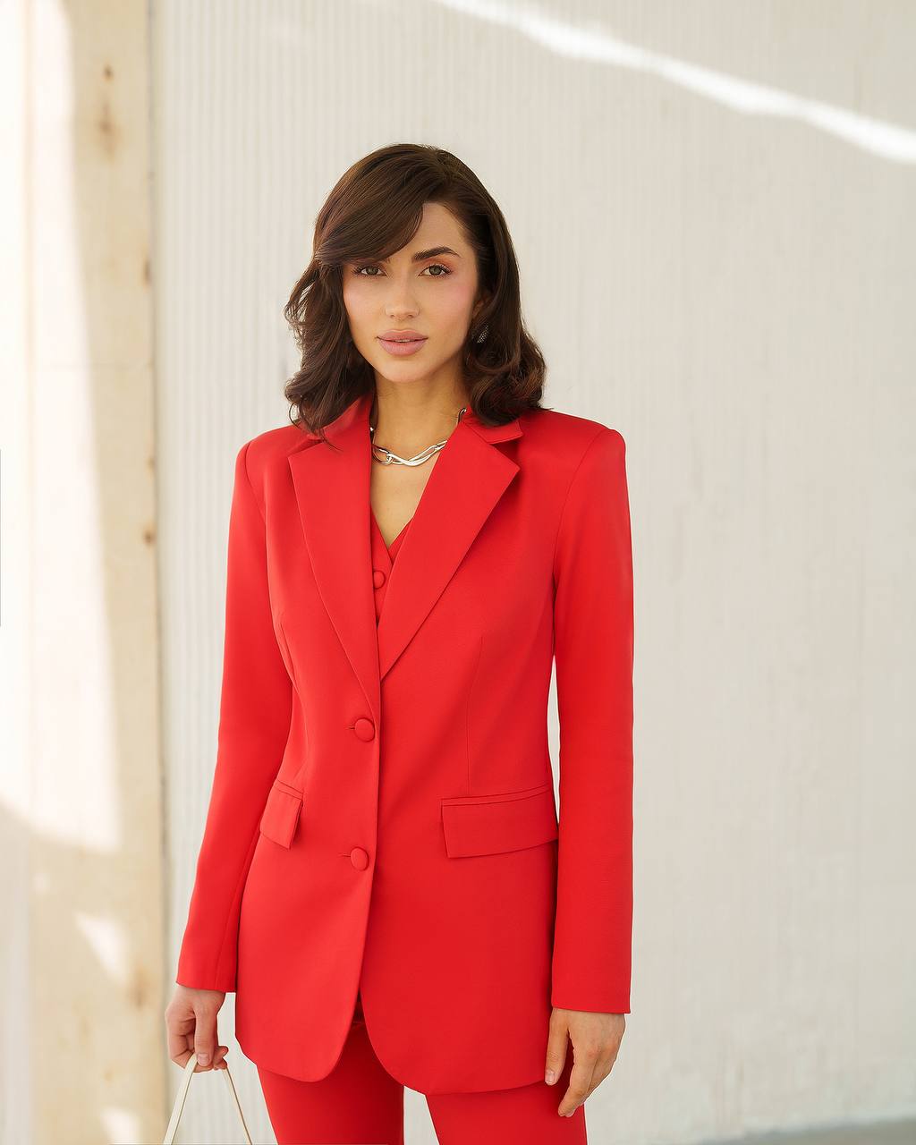 Woman wearing a red suit standing against a light background