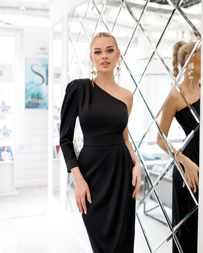 Woman wearing a black one-shoulder dress in front of a mirror.