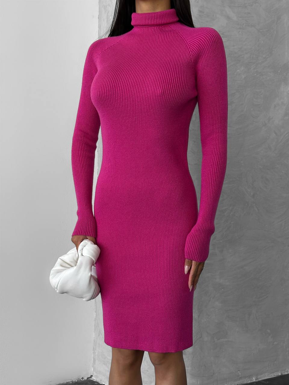 Person wearing a bright pink ribbed dress against a gray background