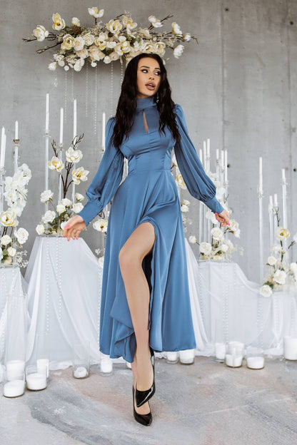 Woman in a blue dress standing in a decorated room with flowers and candles.