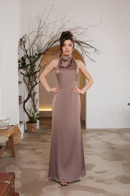 Woman in a long brown dress standing in a room with decorative elements.