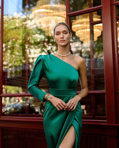 Woman in a green dress standing in front of a window with a blurred outdoor background