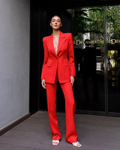 Woman in a red suit standing in front of a building entrance.