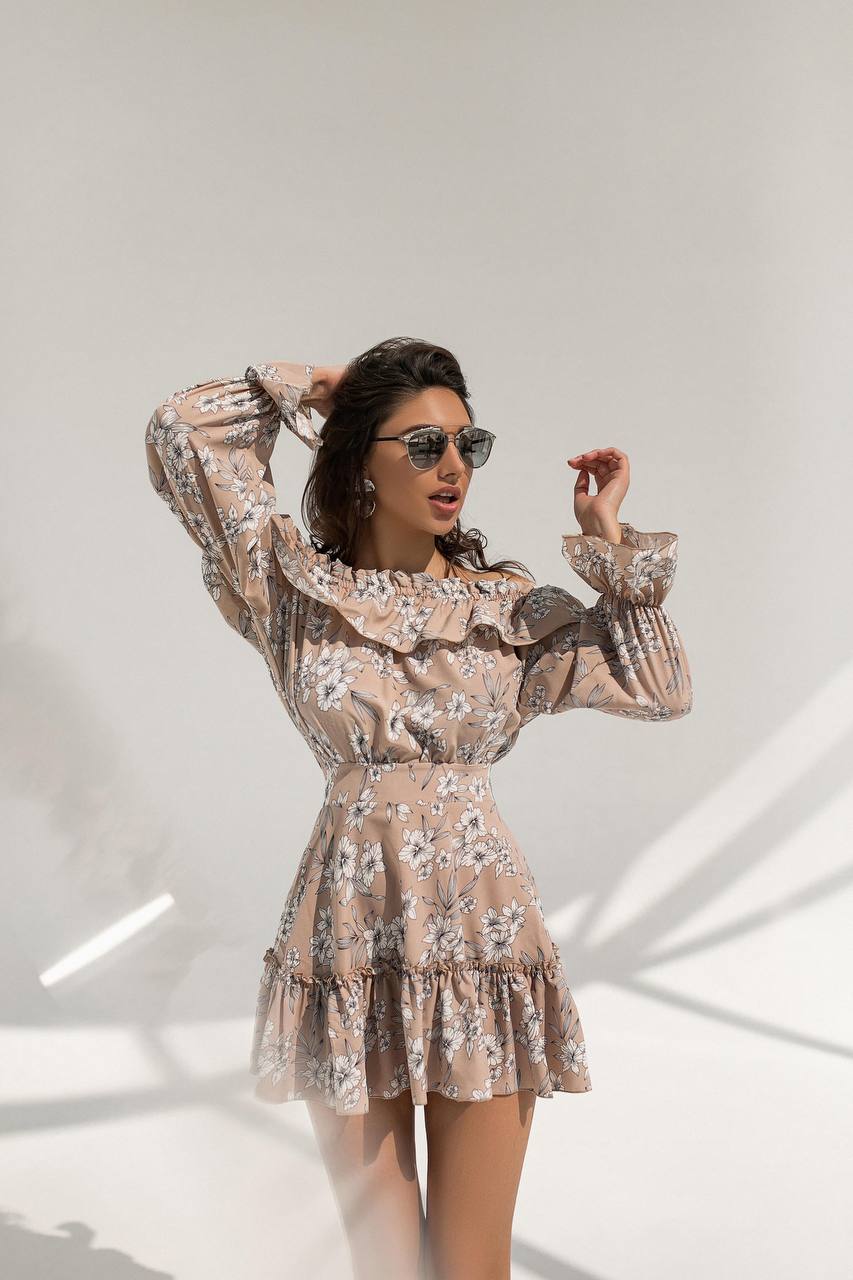 Woman wearing a floral dress with long sleeves against a white background