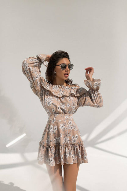 Woman wearing a floral dress with long sleeves against a white background