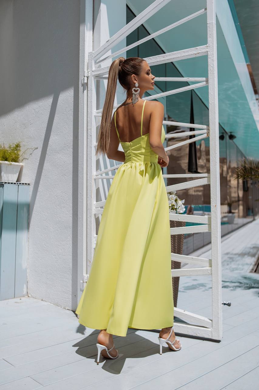 Woman in a yellow dress standing in front of a modern building with white stairs.