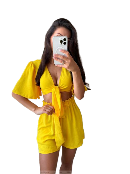 Woman taking a mirror selfie wearing a yellow outfit on a white background