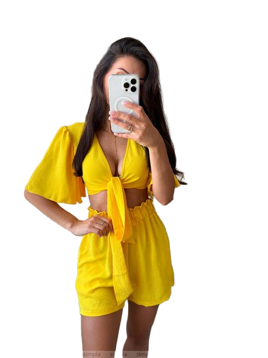Woman taking a mirror selfie wearing a yellow outfit on a white background
