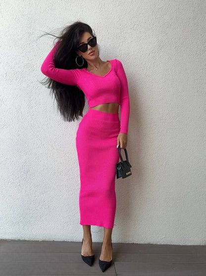 Woman wearing a bright pink outfit against a white wall