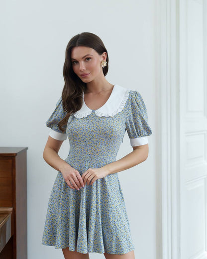 Woman wearing a floral dress with a white collar against a light background