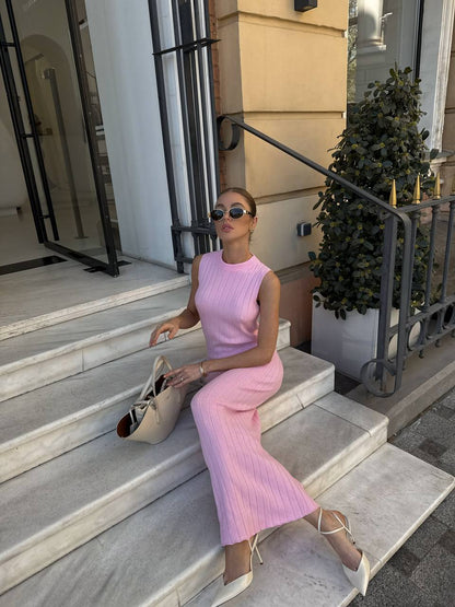 Woman in a pink dress sitting on steps outside a building