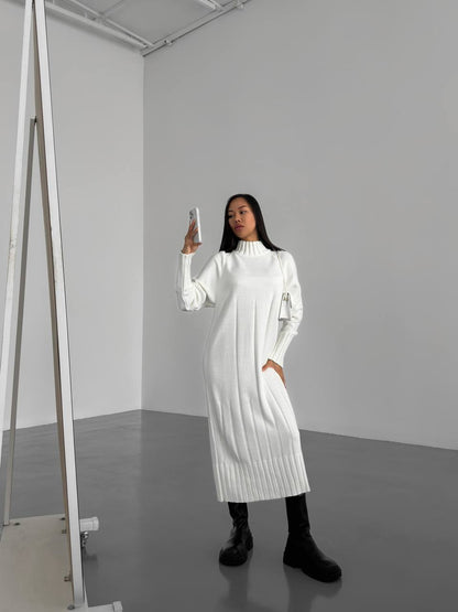Woman in a white dress standing in a minimalistic room.