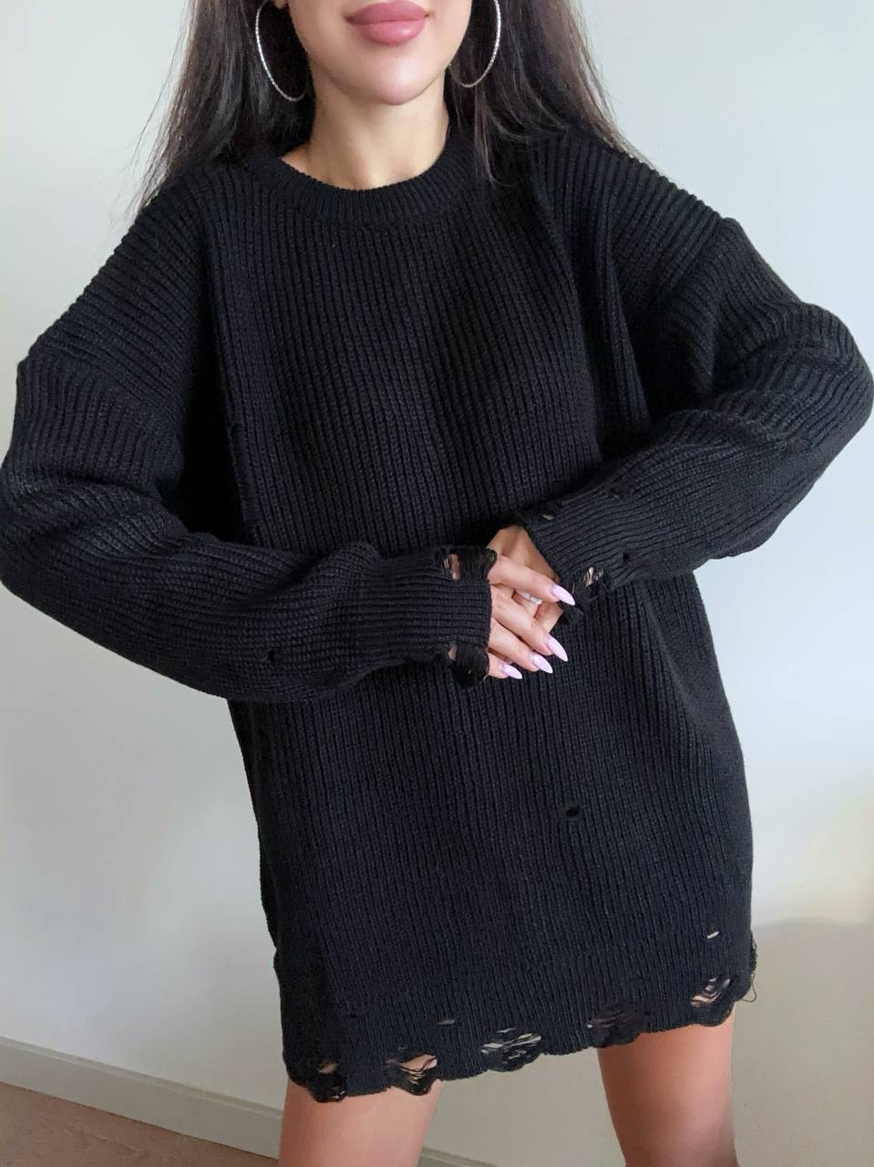 Person wearing a black knit dress with a plain background