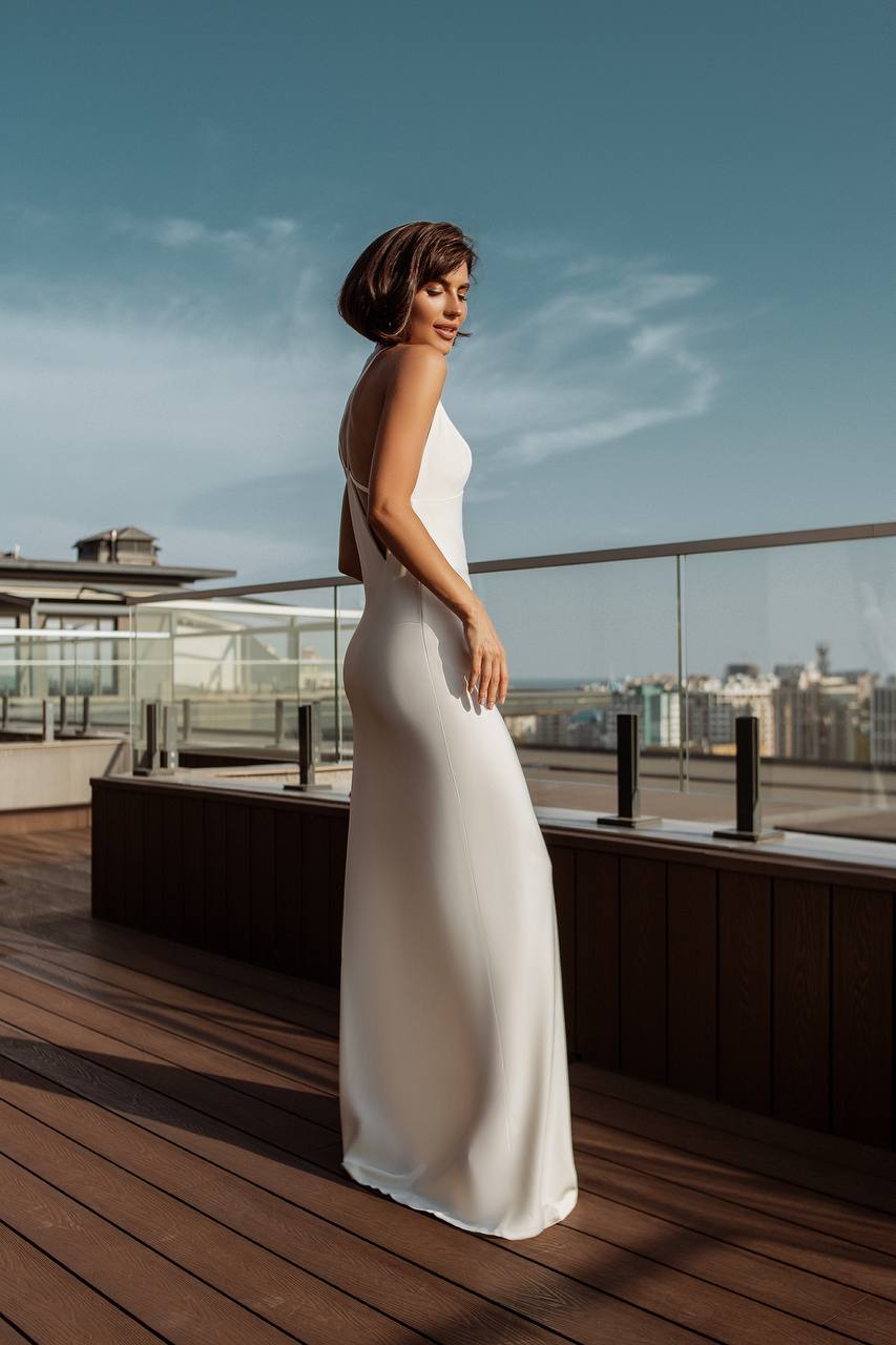 Woman in a white dress standing on a rooftop with a cityscape in the background