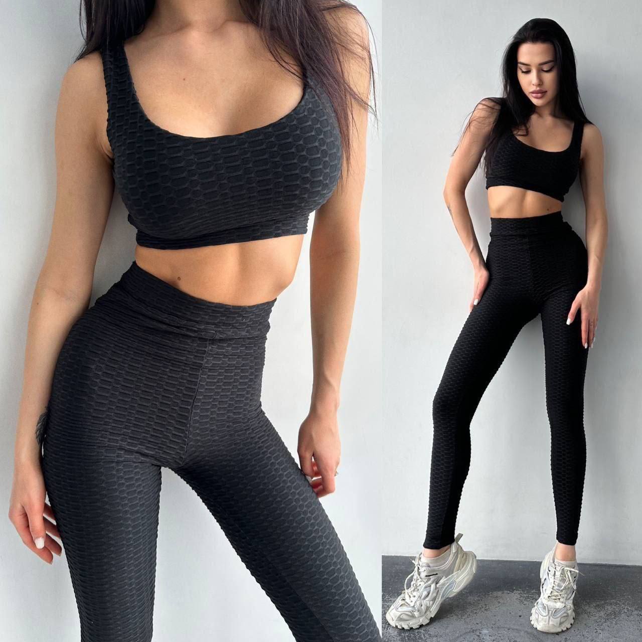 Woman wearing black athletic wear posing against a white background