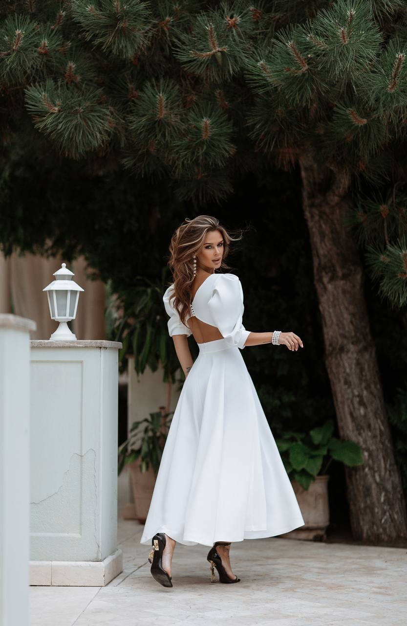 Woman in a white dress standing outdoors with trees in the background