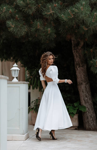 Woman in a white dress standing outdoors with trees in the background