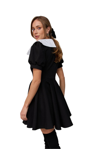 Woman wearing a black dress with a white collar on a white background