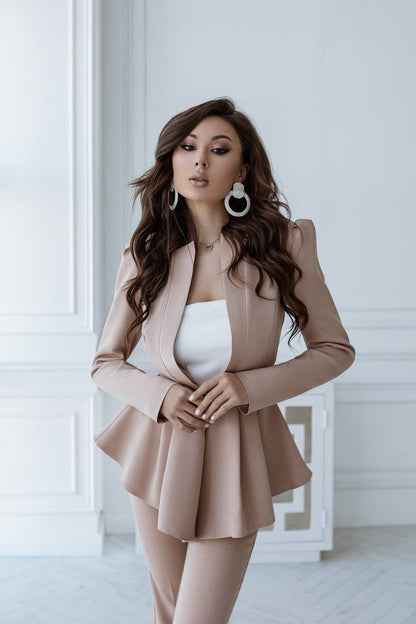 Woman wearing a beige suit with a white top in a minimalistic setting