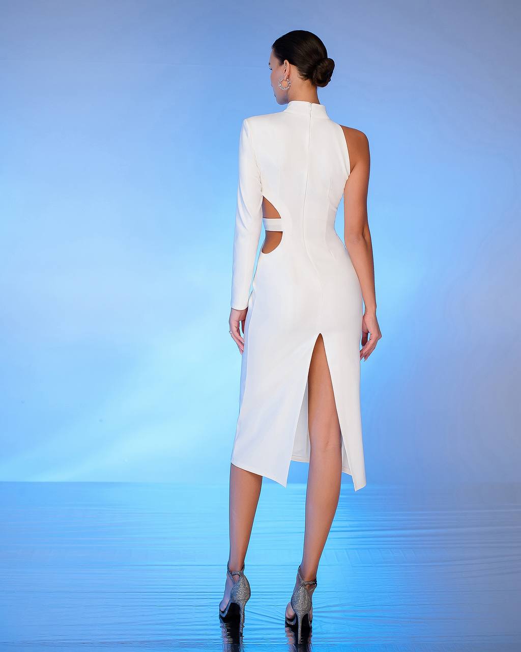Woman wearing a white dress with cut-out design on a blue gradient background