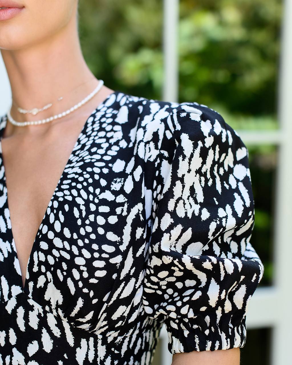 Black and white patterned top worn by a person with a blurred background
