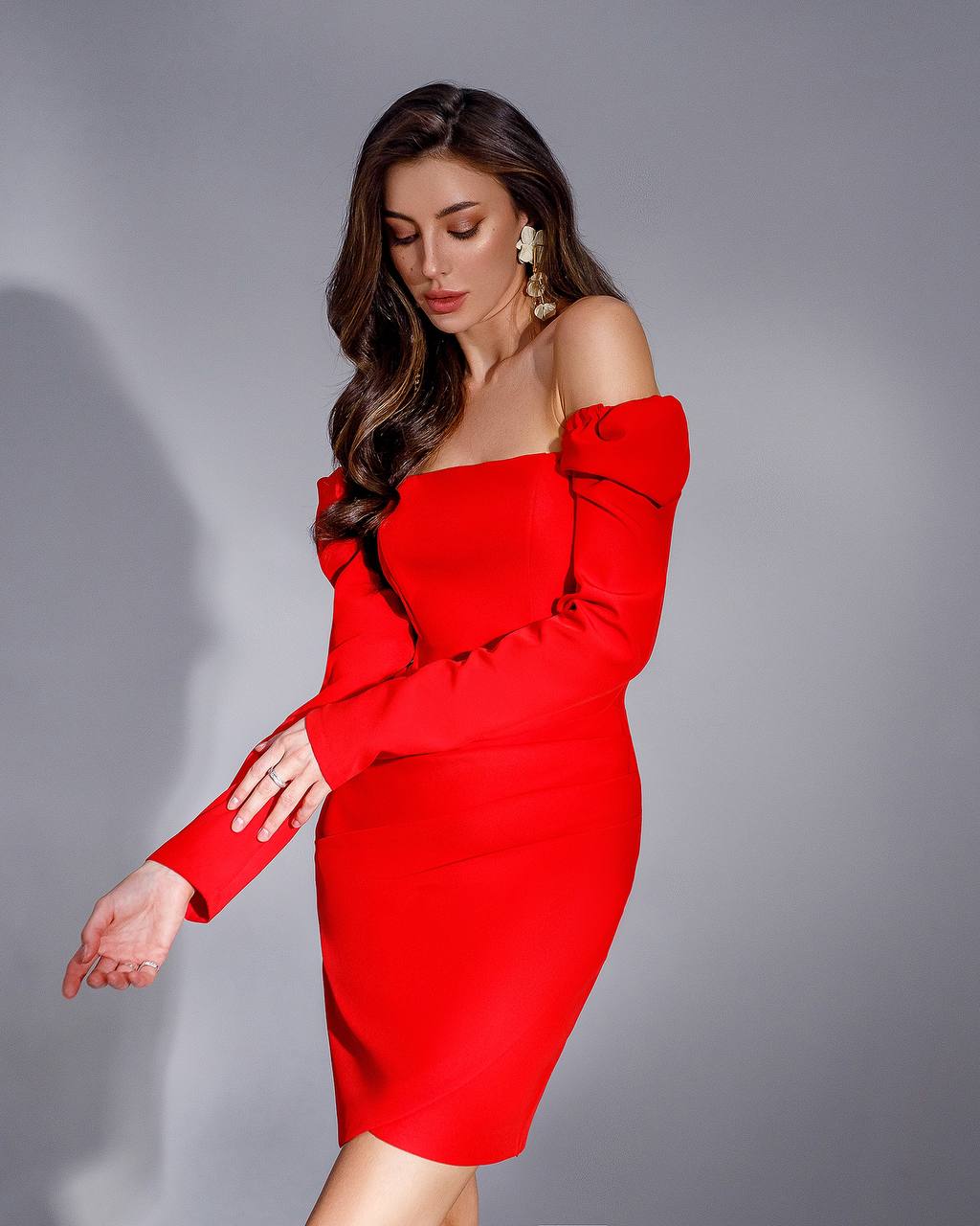Woman wearing a red off-shoulder dress against a gray background
