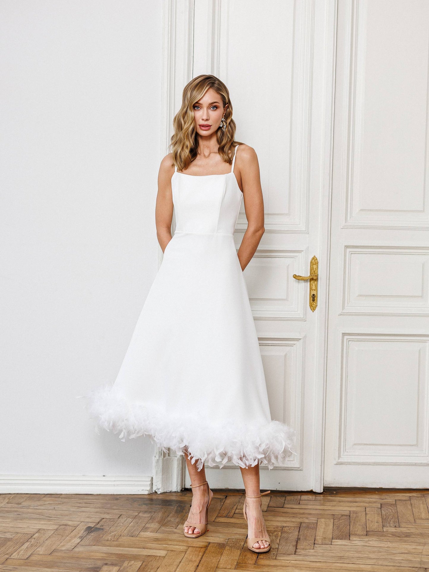 Woman in a white dress standing in front of a white door.