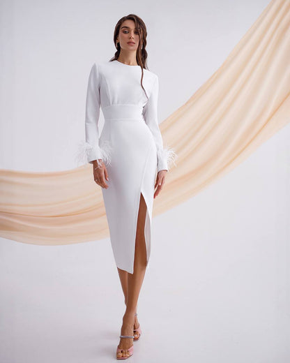 Woman wearing a white dress with a high slit on a plain background