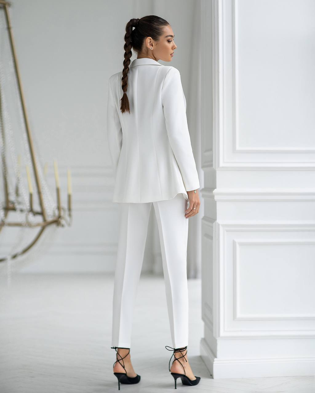 Woman wearing a white suit in a minimalistic room.