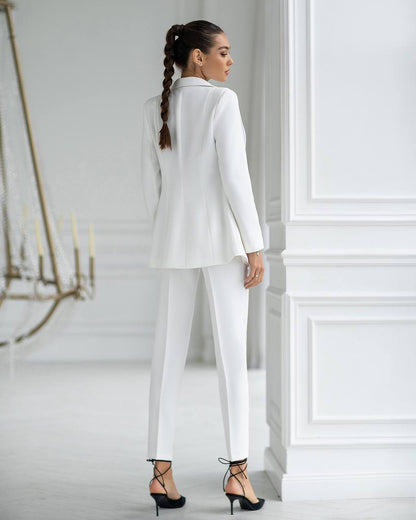 Woman wearing a white suit in a minimalistic room.