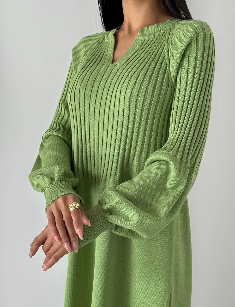 Green ribbed sweater dress worn by a person on a plain background