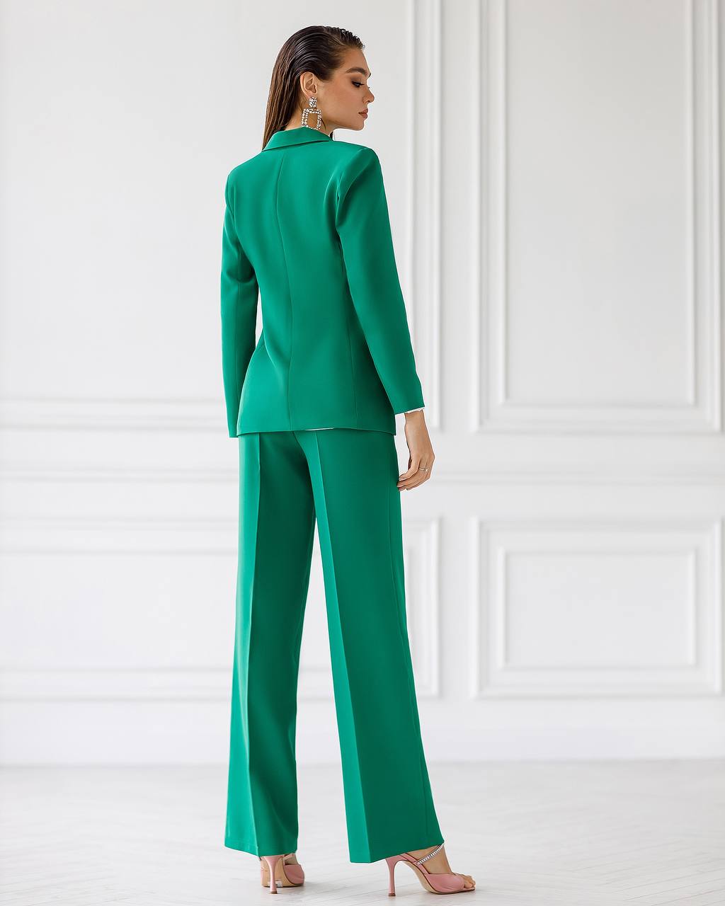 Woman wearing a green suit against a white wall