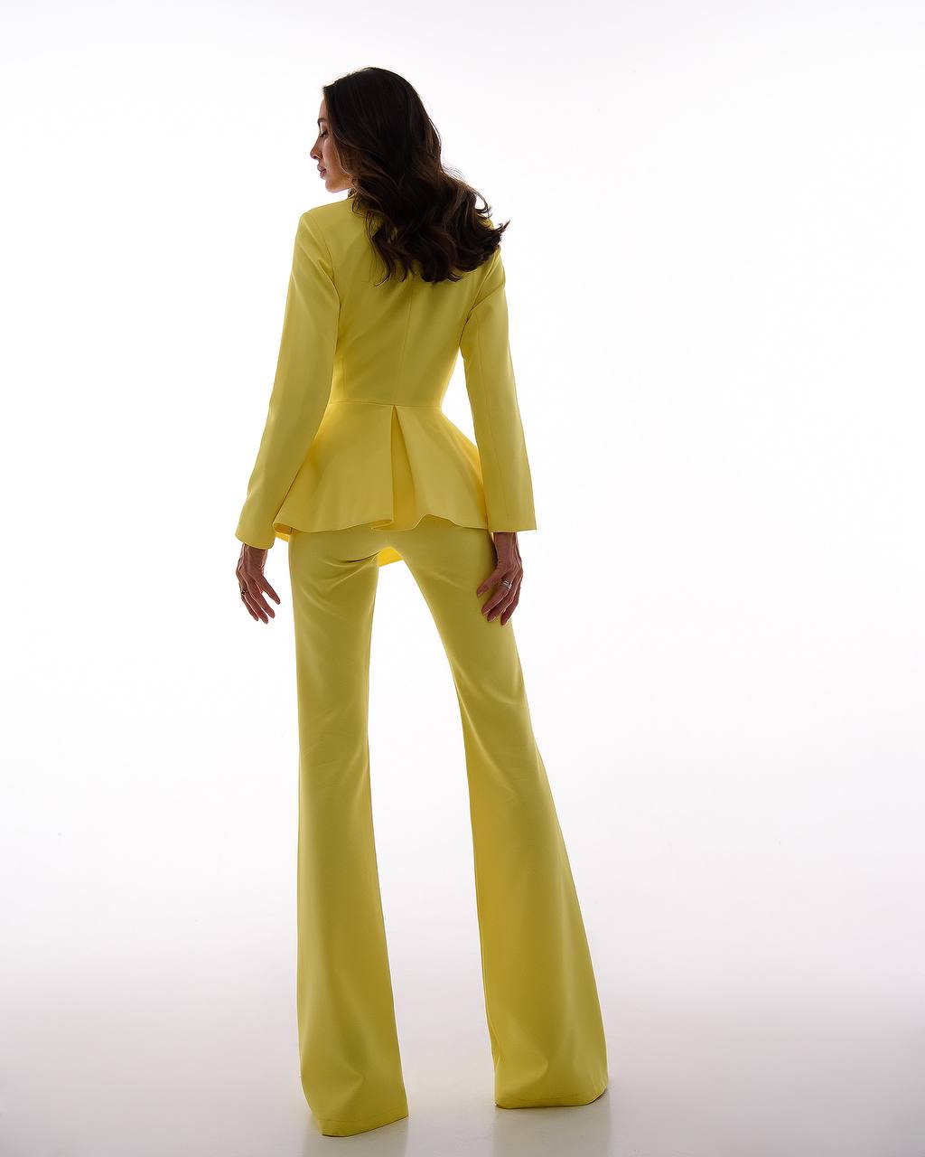 Woman wearing a bright yellow suit on a white background
