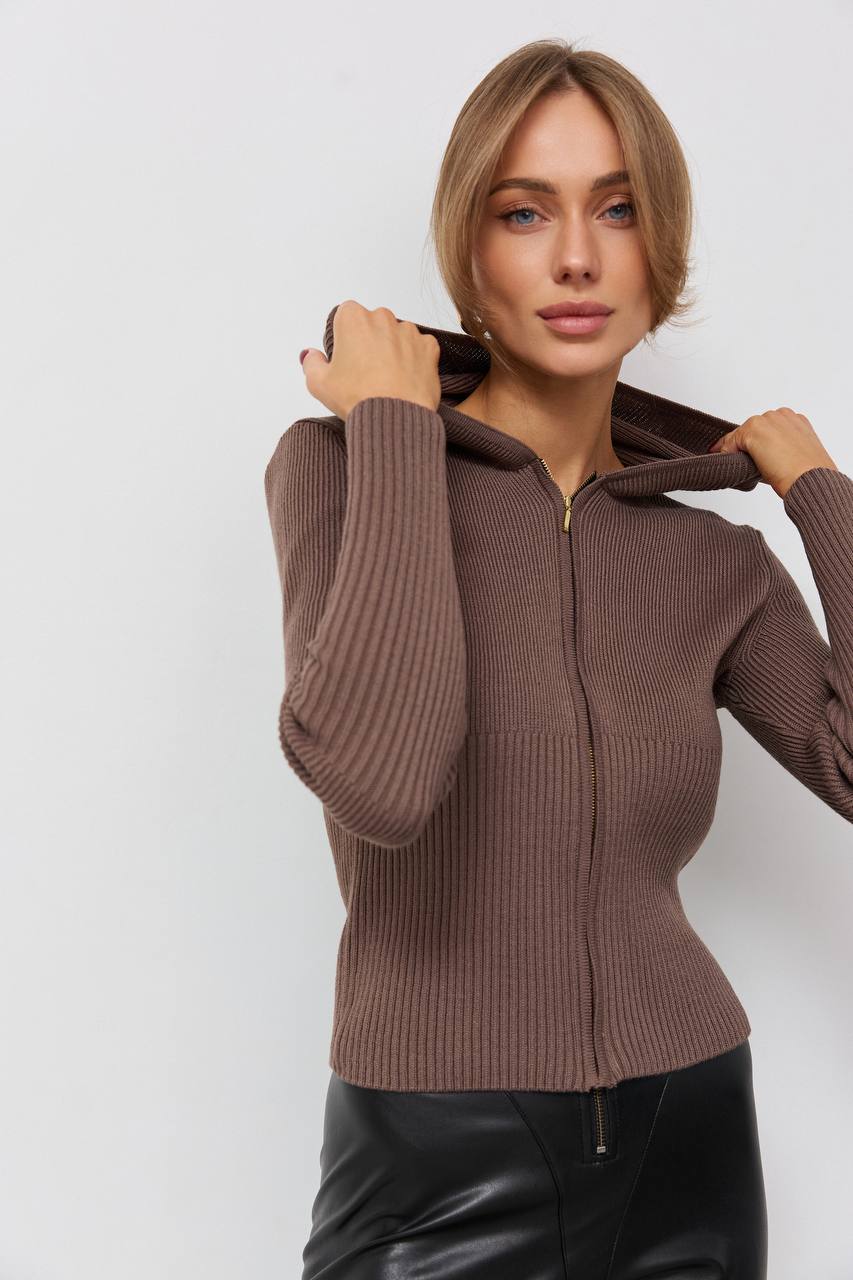 Woman wearing a brown ribbed sweater against a white background