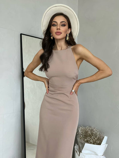 Woman wearing a beige dress and white hat in front of a mirror.