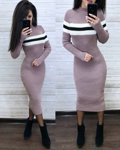 Woman wearing a pink ribbed knit dress with black and white stripes, standing in front of a wooden panel wall.