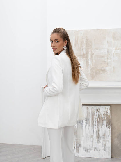 Woman in a white outfit standing in a minimalistic room with abstract art on the wall.
