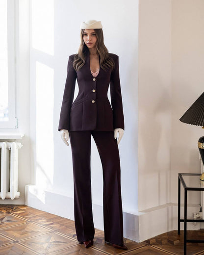 Woman in a dark suit standing in a room with a lamp and window in the background