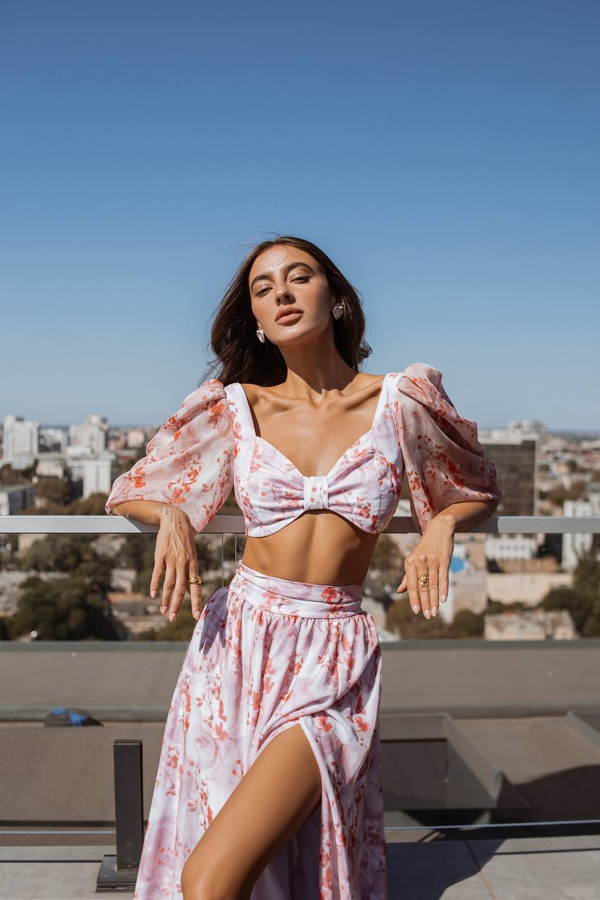 Woman in a floral outfit standing on a rooftop with a cityscape in the background