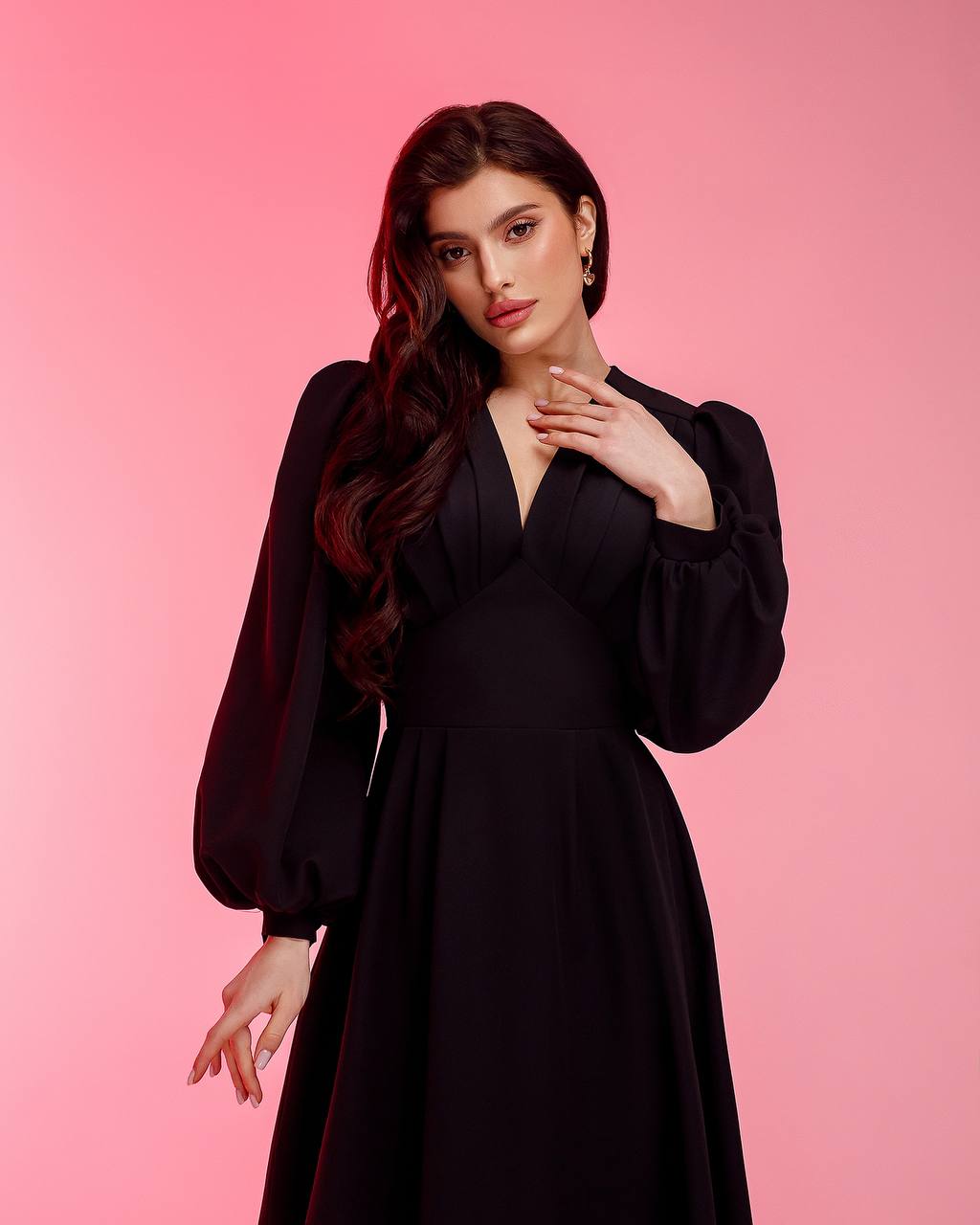 Woman wearing a black dress against a pink background