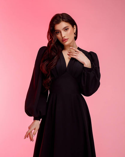 Woman wearing a black dress against a pink background