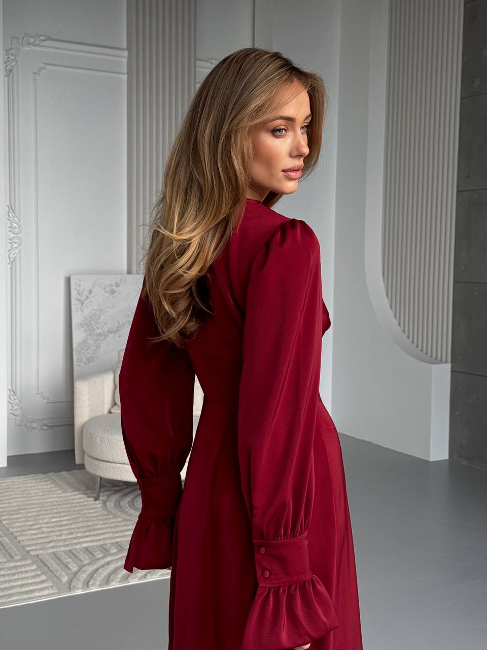 Woman in a red dress standing in an elegant interior setting