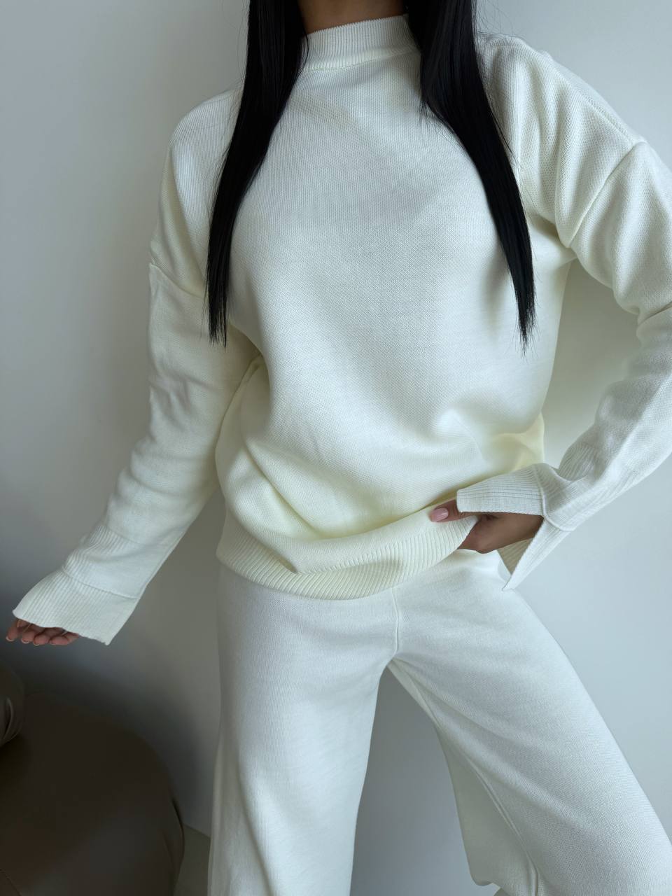 Person wearing a white sweater and pants against a plain background